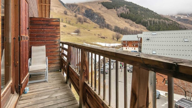 A wooden balcony with a view of a mountainous landscape.