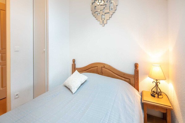 A neatly made bed with a wooden headboard, a bedside lamp, and a decorative wall piece.
