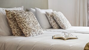 A neatly made bed with floral-patterned pillows and a book with glasses on it. - Aura Serena by Madeira Sun Travel (Santa Cruz)