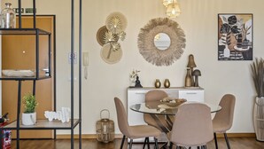 A modern dining area with a round table, four chairs, and decorative wall art. - Aura Serena by Madeira Sun Travel (Santa Cruz)