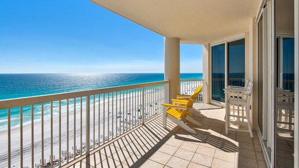 A balcony with a view of the beach and ocean.