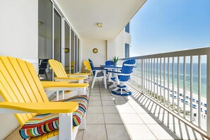 A balcony with yellow and blue chairs, a small table, and a potted plant. - Silver Beach Towers 1003 West (Destin)