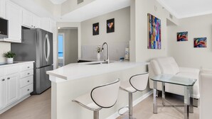 A modern kitchen with white cabinetry, stainless steel appliances, and a central island with bar stools.