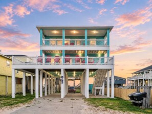 A multi-level building with a covered walkway, numbered 845, and a staircase leading to the upper levels. - 2nd Row Crystal Beach Home | Steps Away | Sleeps 18 (Crystal Beach)