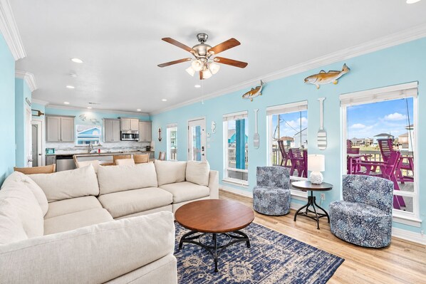 A spacious living area with a sofa, a coffee table, patterned chairs, and a view of the outside.