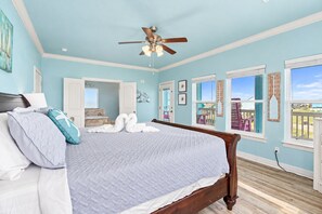 A bedroom with a bed, a ceiling fan, and a view of the outdoors. - 2nd Row Crystal Beach Home | Steps Away | Sleeps 18 (Crystal Beach)