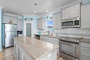 A kitchen with white cabinets, a granite countertop, stainless steel appliances, and a tiled backsplash.