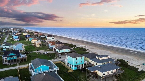 A coastal residential area with houses along the beach, featuring a mix of single and multi-story buildings, some with porches and visible landscaping. - 2nd Row Crystal Beach Home | Steps Away | Sleeps 18 (Crystal Beach)