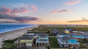 A coastal residential area with houses along the beach, featuring a mix of single and multi-story buildings with balconies.