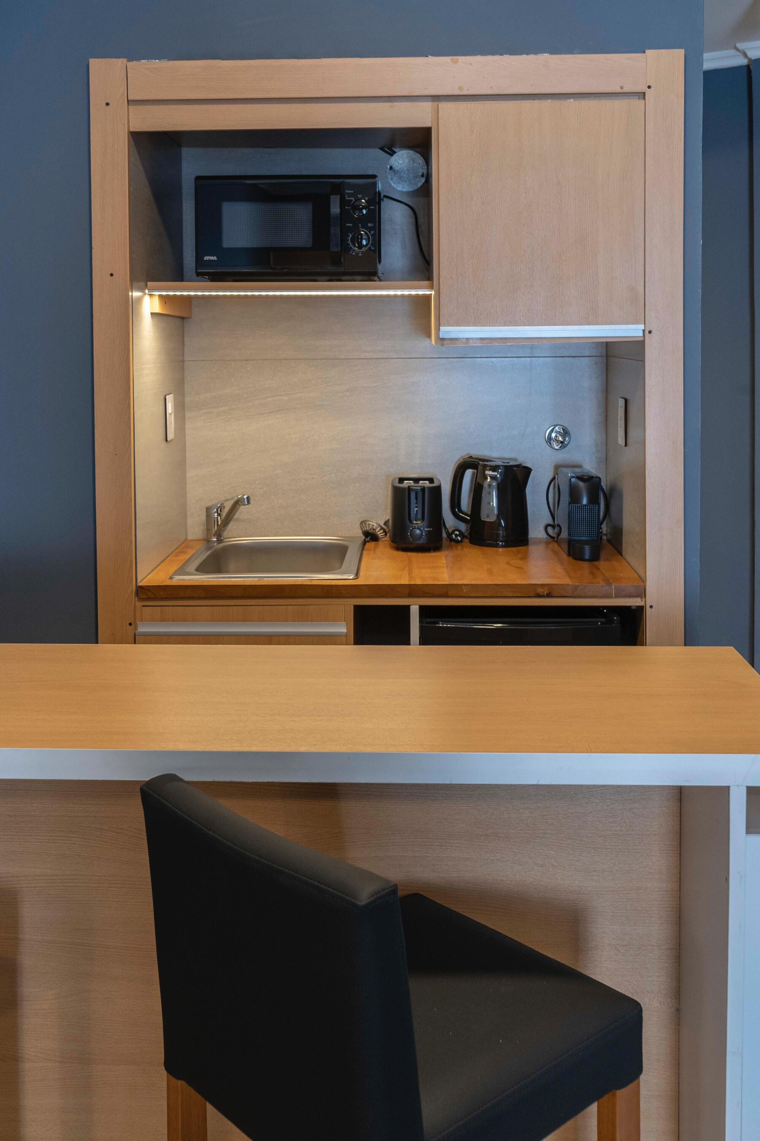 A compact kitchenette with a microwave, toaster, kettle, and coffee maker.
