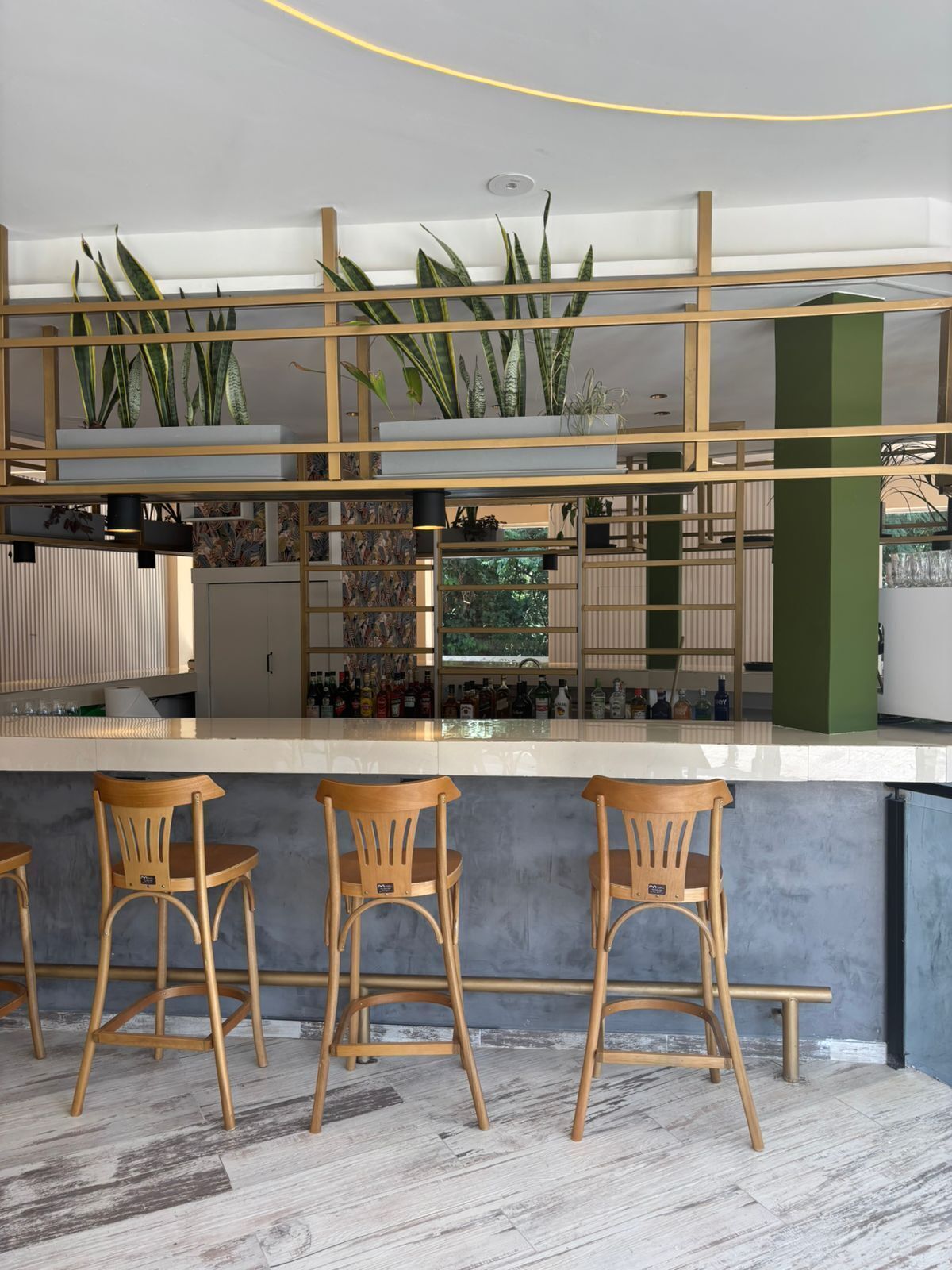 Angolo bar con sedie in legno e un bancone che espone bottiglie.