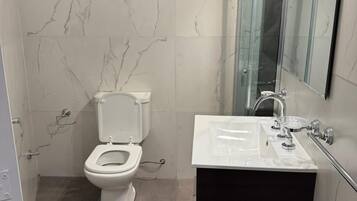 Une salle de bain moderne avec des toilettes, un lavabo et un grand miroir.