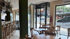Una cafetería moderna con muebles de madera, una barra y amplios ventanales con vistas a la calle.