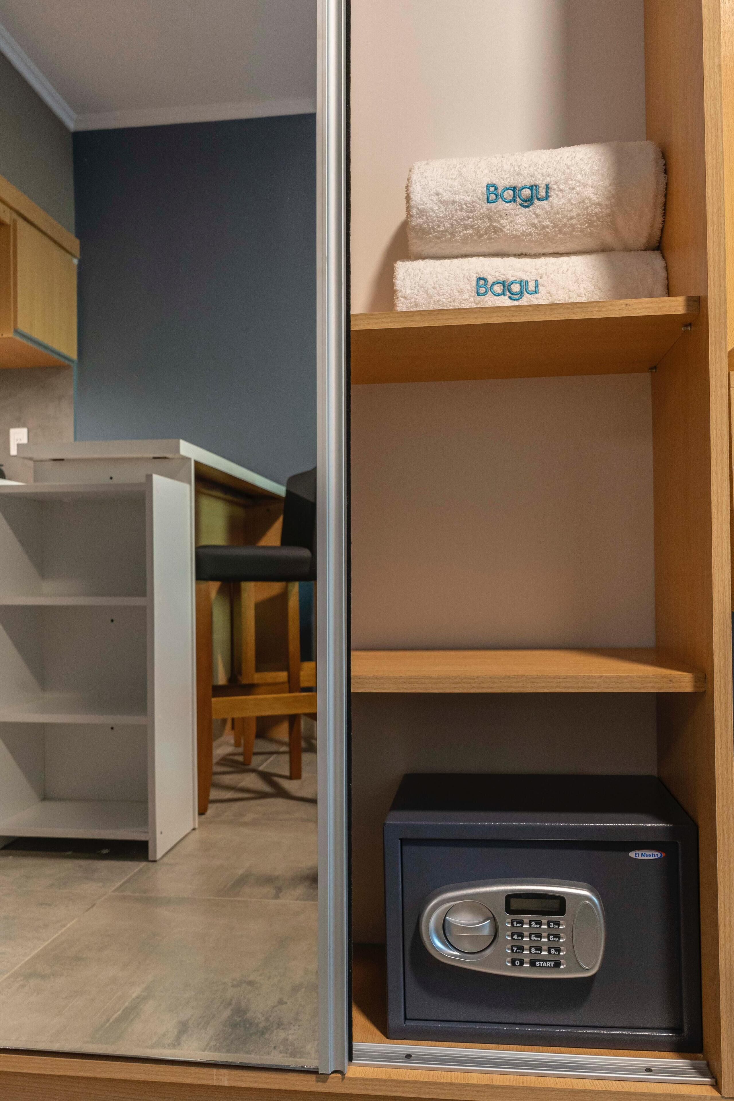 A room with a wooden cabinet, a black safe, and two towels labeled 'Bagu'.