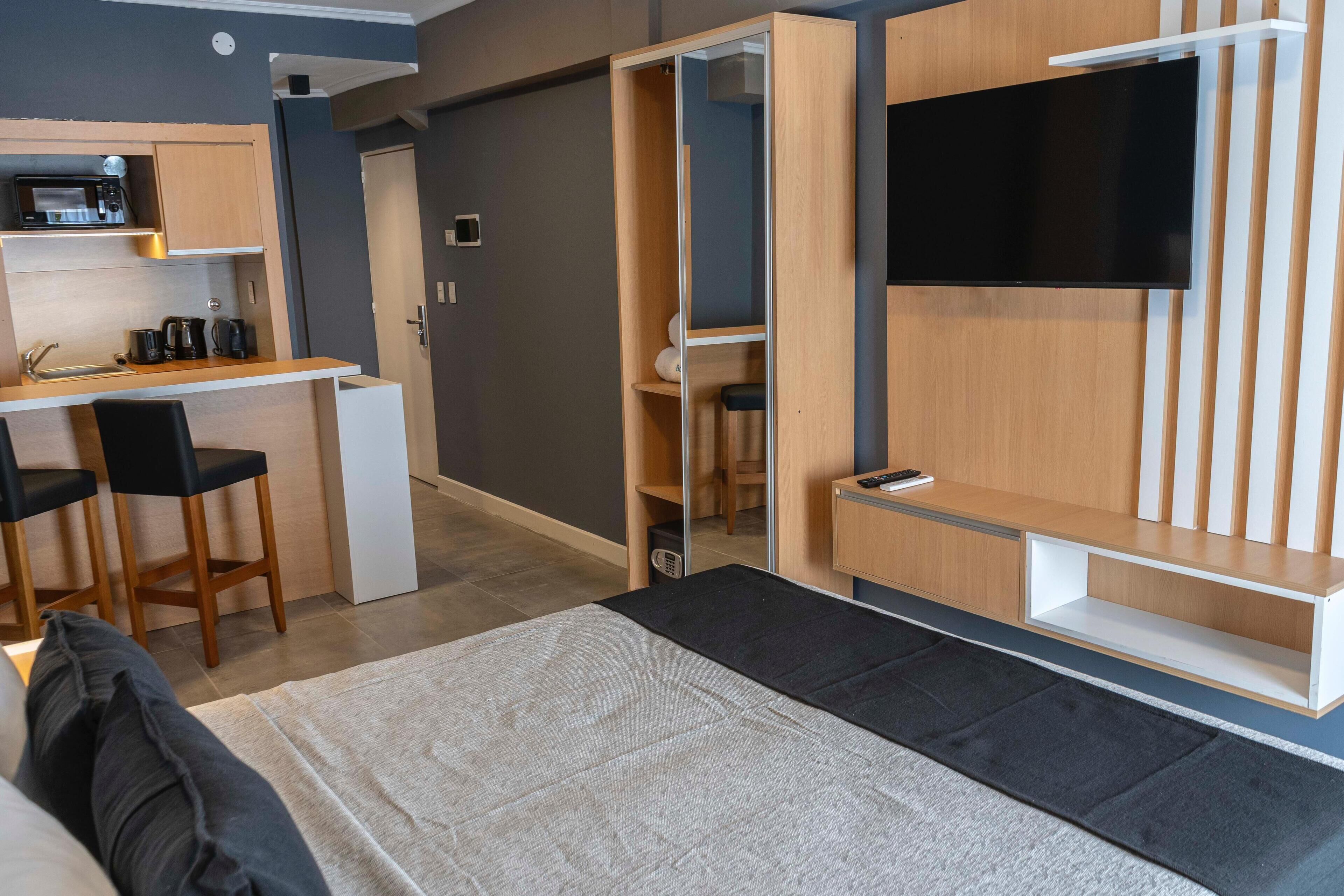 Una habitación pequeña con cama, escritorio, silla, televisor y armario.