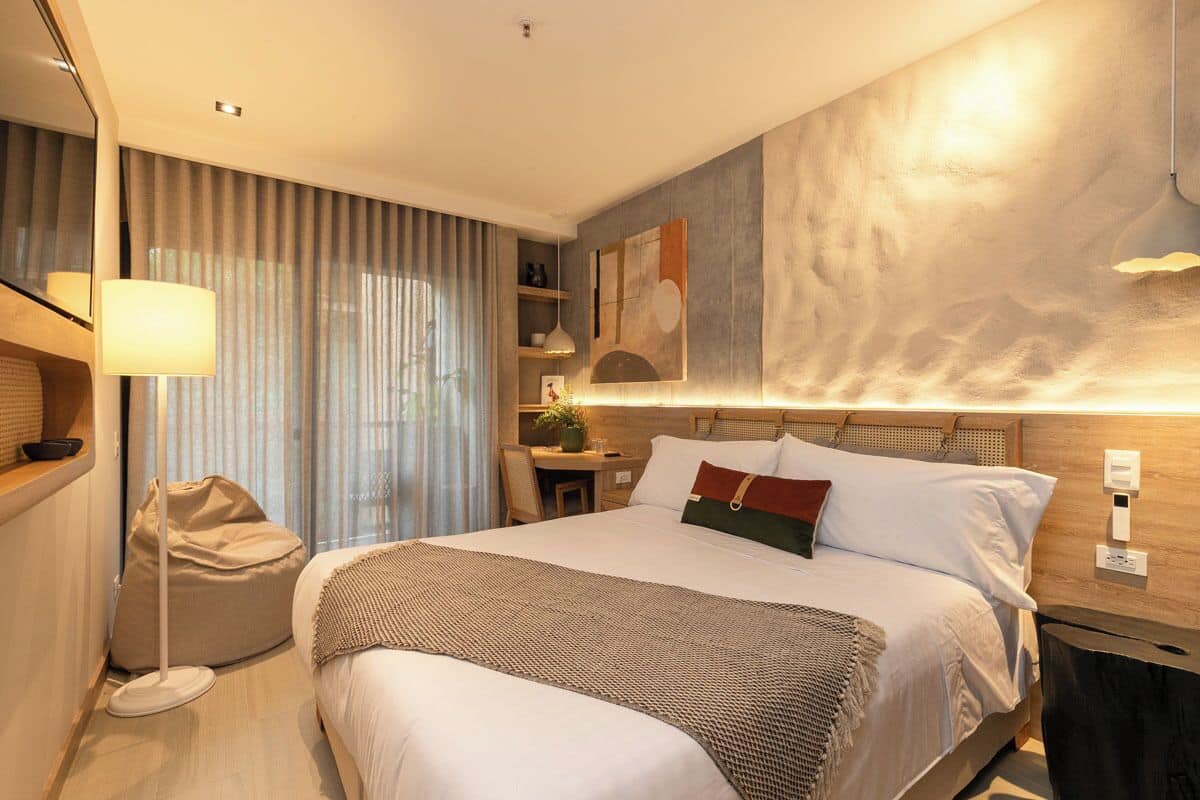 A modern hotel room with a large bed, a desk, a chair, and a bean bag.