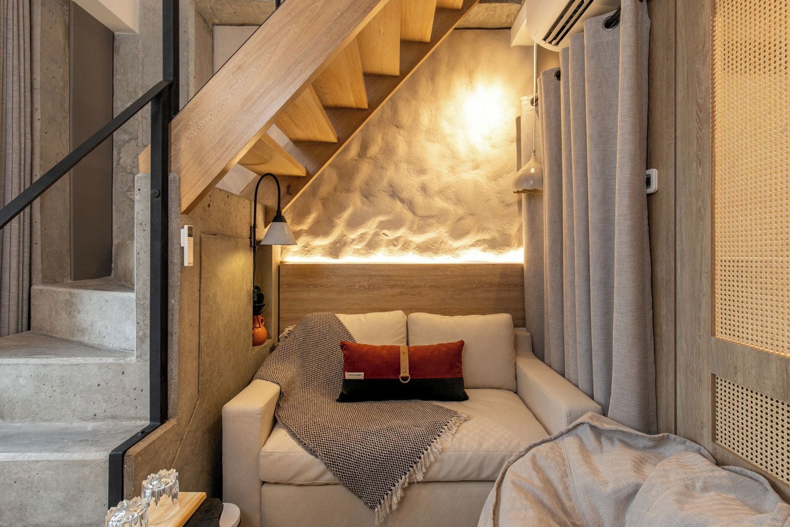 A cozy bedroom with a built-in bed, a wooden staircase, and a textured wall.