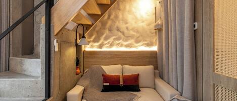 A cozy bedroom with a built-in bed, a wooden staircase, and a textured wall.