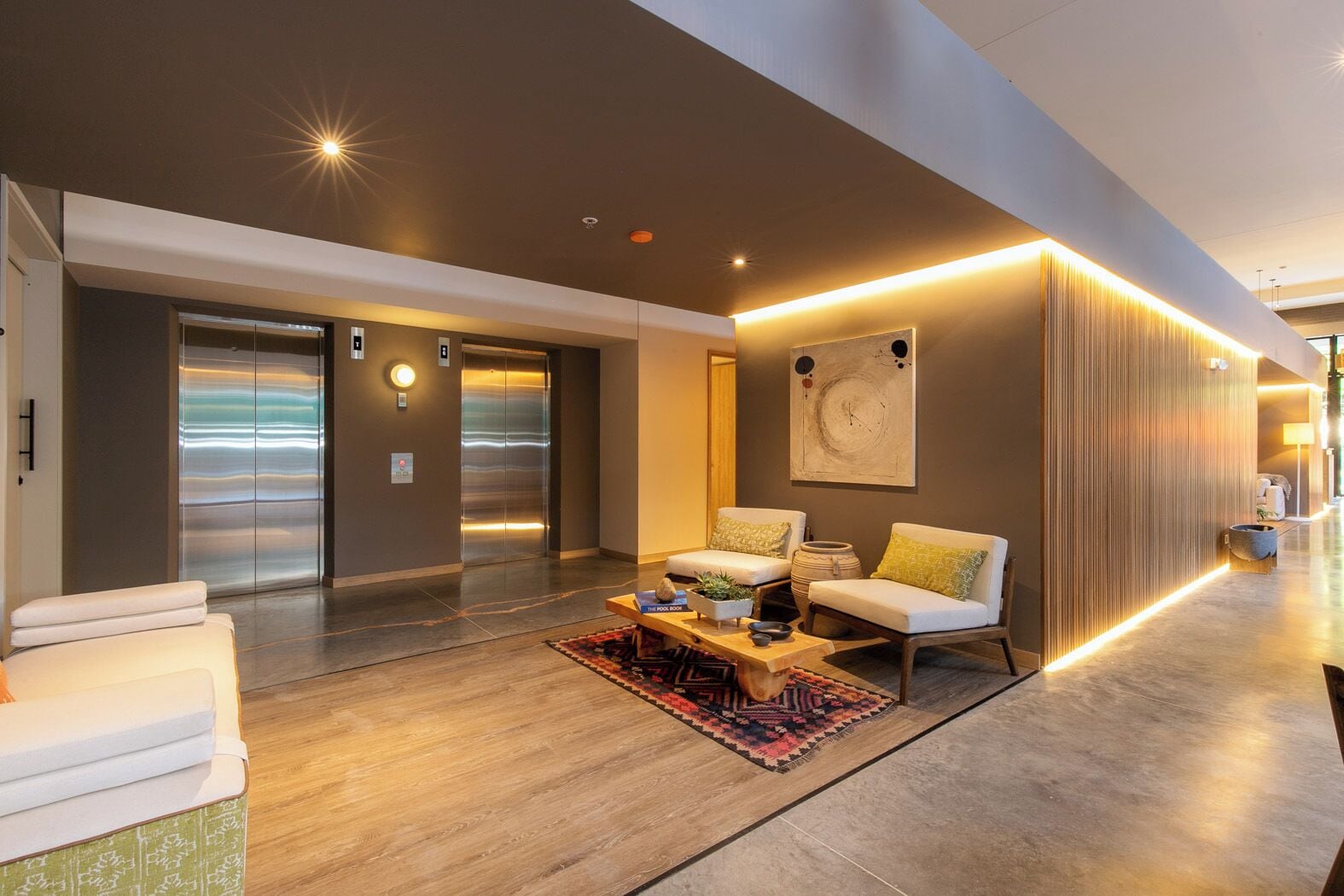 A modern lobby with a sofa set, a coffee table, and a large abstract painting on the wall.
