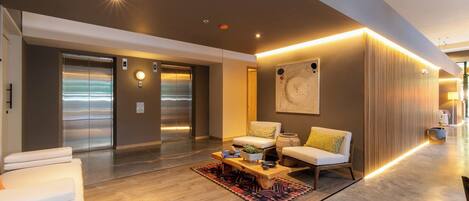 A modern lobby with a sofa set, a coffee table, and a large abstract painting on the wall.