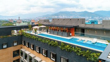 A rooftop pool with a view of a cityscape and mountains in the background.