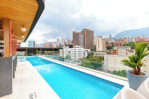 Una piscina al aire libre, sombrillas, sillones reclinables de piscina