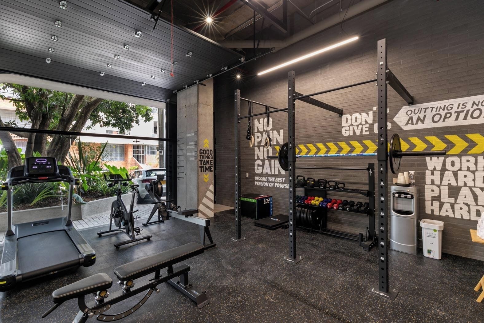 Ein Fitnessstudio mit Trainingsgeräten, motivierenden Wandbildern und Blick ins Freie.
