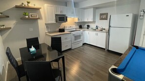 Una cocina moderna con armarios blancos, microondas, refrigerador y un comedor con mesa y sillas.