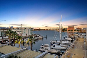 A marina with boats docked, a building with a flat roof, and a clear sky.