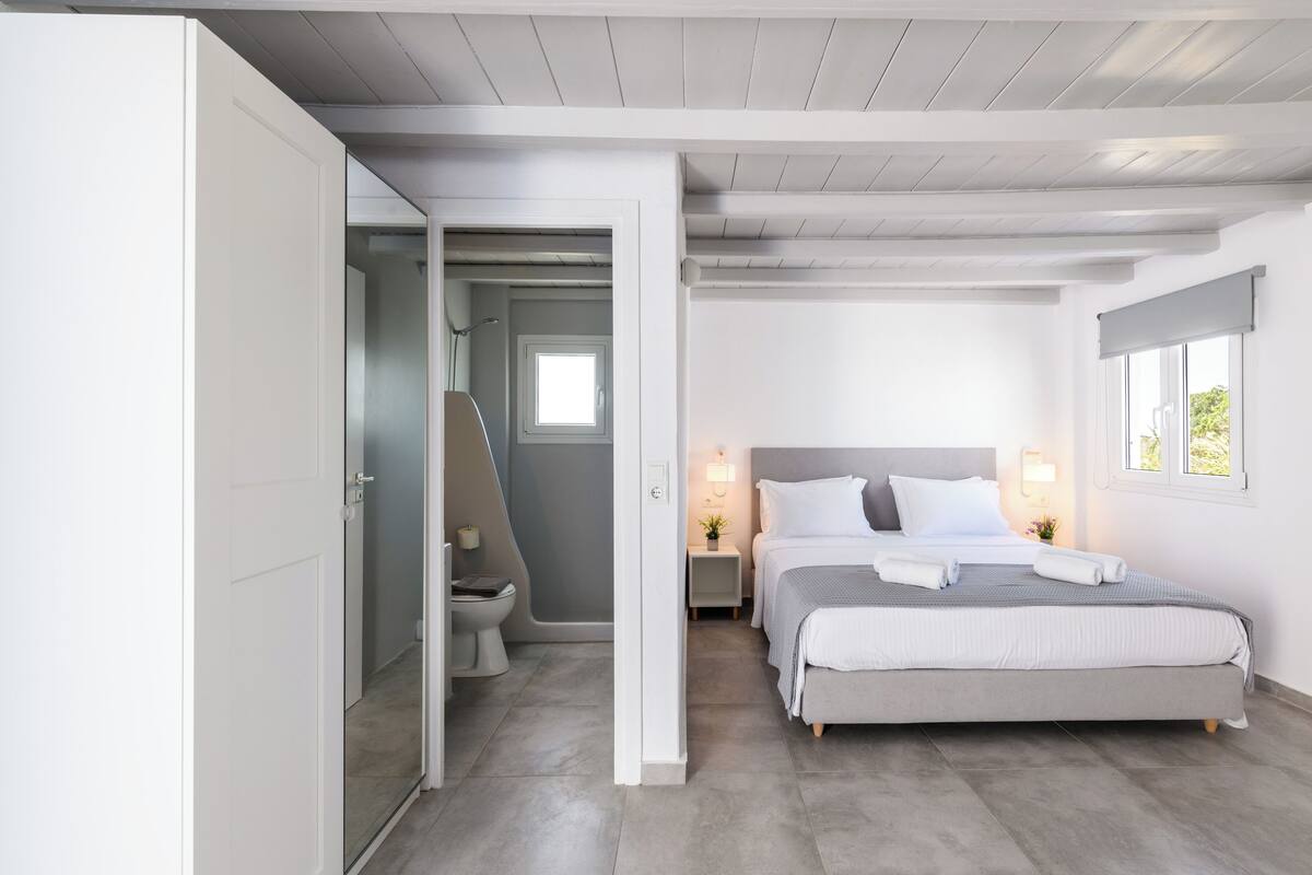 A bedroom with a bed, bedside tables, a window, and a door leading to a bathroom.