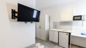Una kitchenette compacta con una televisión de pantalla plana, un microondas y un refrigerador pequeño.