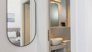 Un baño moderno con un espejo redondo, un lavabo blanco y un inodoro.