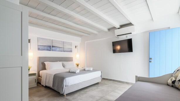 Un dormitorio moderno con cama, mesitas de noche, televisión y armario.