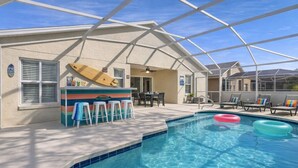 A pool area with a bar, lounge chairs, and a covered patio.