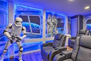 Experience the futuristic ambiance in this stylish room, featuring a space-themed mural and comfortable black leather sofas.