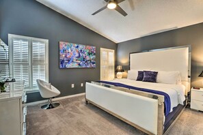 Relax in this serene bedroom with a large bed, ceiling fan, and comfortable chair.