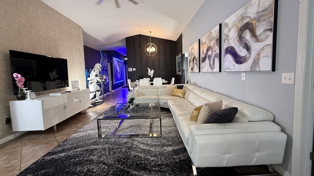 A modern living room with a sectional sofa, a flat-screen TV, and abstract wall art.