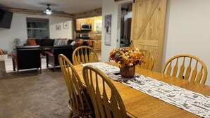 A dining area with a wooden table, four chairs, and a vase of flowers. - Cozy 3-bedroom cabin in charming North East (North East)