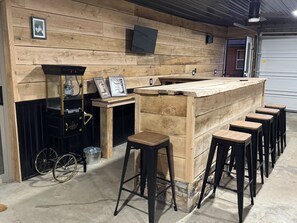 A bar area with wooden stools, a bar counter, and a jukebox. - Cozy 3-bedroom cabin in charming North East (North East)