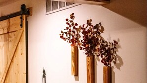 A room with a wooden door, a wall-mounted vent, and three wooden vases with dried flowers. - Cozy 3-bedroom cabin in charming North East (North East)