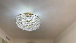 Um corredor com um candelabro, uma porta de madeira e uma escadaria.