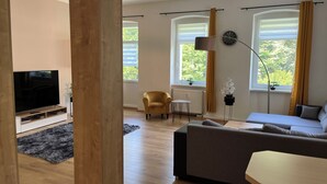 Uma sala de estar moderna com televisão de tela plana, sofá, poltrona e uma mesinha.