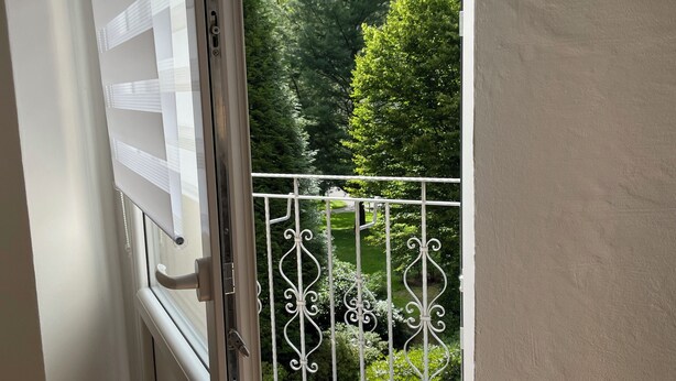 Varanda com guarda-corpo de metal e vista para uma paisagem verdejante.