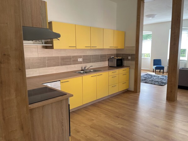 Une cuisine moderne avec des meubles de couleur jaune, un four à micro-ondes et un lave-vaisselle.