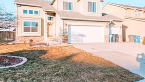 A two-story house with a garage, a front yard with a landscaped area, and a driveway. - Hot Tub, King Beds, Pet Friendly Close to I25 (Fountain)