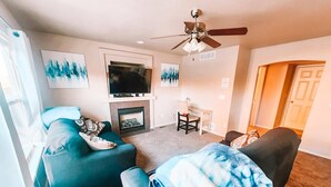 A living room with a fireplace, a TV, and a ceiling fan. - Hot Tub, King Beds, Pet Friendly Close to I25 (Fountain)