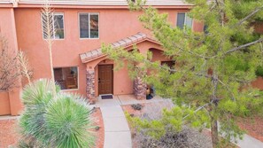 A two-story building with a stucco exterior, a stone entrance, and a small porch. - Kanab Pad F4 – Pool, Hot Tub & Gym Access (Kanab)
