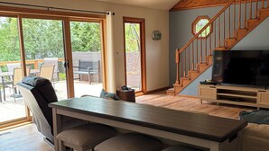 A modern kitchen with a bar area, a staircase, and a large TV. - Charming Lake House! (Wild Rose)