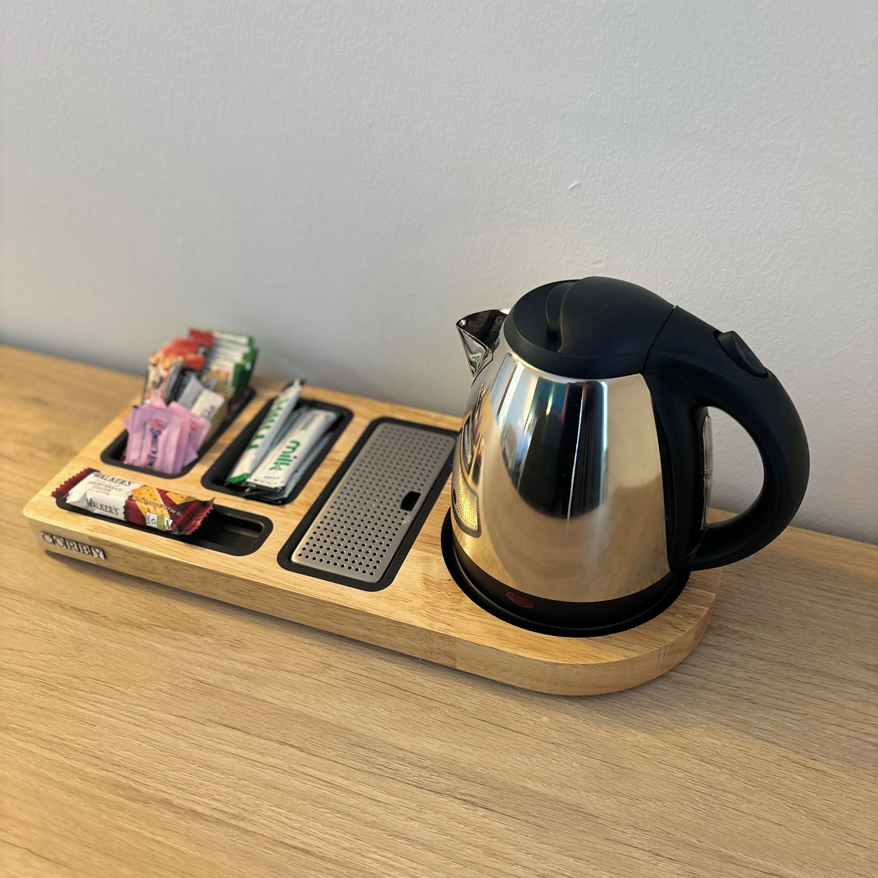 A stainless steel kettle on a wooden tray with a perforated tray and a small compartment for snacks.