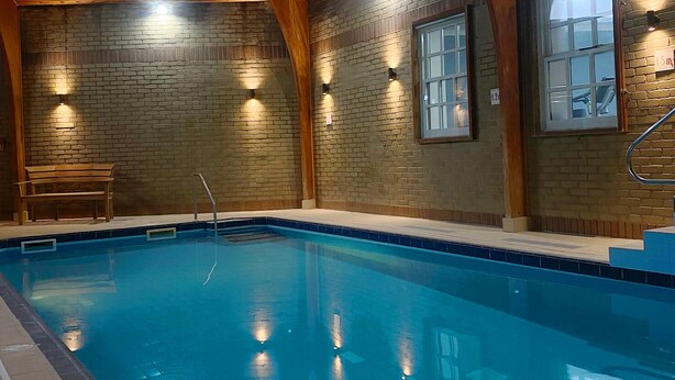 An indoor swimming pool with wooden beams and brick walls, benches, and built-in lighting. - Lomond Hills Hotel & Health Club  (Cupar)